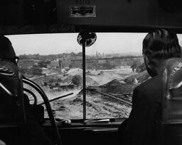 <p>Governor Thomas Stanley observes the construction progress of the Richmond-Petersburg Turnpike from a tour bus on May 9, 1957. Stakeholders in the project gave the governor the tour of all the construction zones—including a drive on a stretch of the finished roadway. In this photograph the tour group is in Shockoe Valley, looking toward the Marshall Street viaduct in downtown Richmond.</p> 