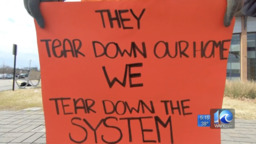 <p>A protester holds a sign which reads: “They tear down our home we tear down the system,” outside of a 2019 meeting between the Norfolk Redevelopment and Hg Authority (NRHA) and representatives from the U.S. department of Housing and Urban Development (HUD).</p>