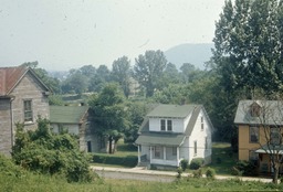 <p>A well-maintained and freshly painted home sits across from a more dilapidated looking house with a rusty roof in this Roanoke Redevelopment and Housing Authority photograph of a street in Gainsboro. The presence of poorly maintained properties in the vicinity of a home was used as justification for lower property valuation by city officials, even if the homeowner had put a great deal of money into the maintenance of their property.</p> 